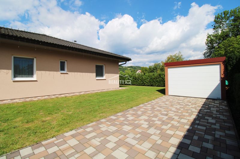 A family house in Bytča with a garden and a garage on a paved area.