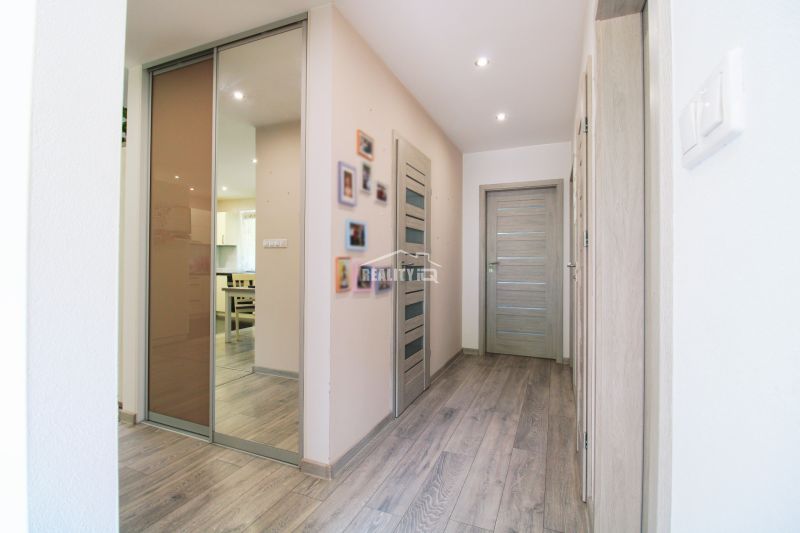 A hallway in a family house with a wooden decor floor and many doors.