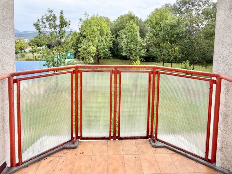 A balcony with a transparent railing and a view of greenery in a 2-room apartment on Mateja Bela in Žilina.