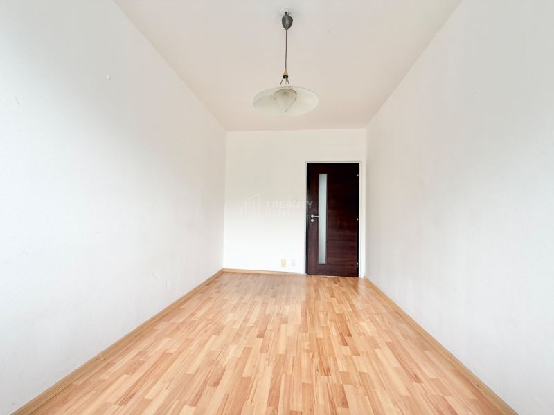 A room in a 2-room apartment with white walls and a wooden decor floor.