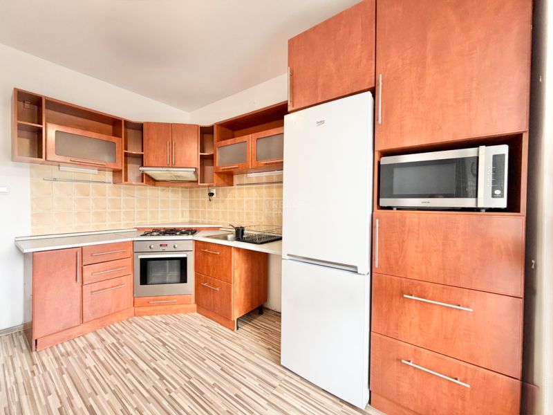 A kitchen in a 2-room apartment with a wooden decor, a stove, and a microwave.