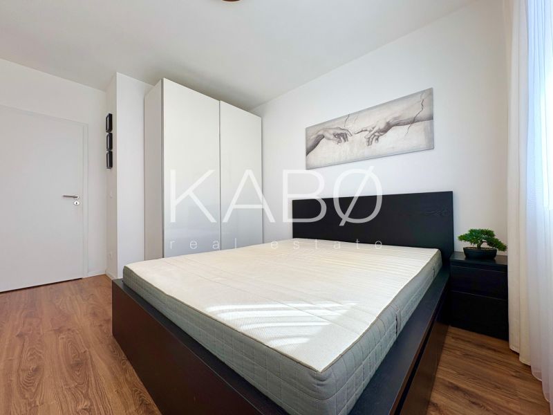 Bedroom in a 2-room apartment with a bed, wardrobe, and wooden decor flooring.