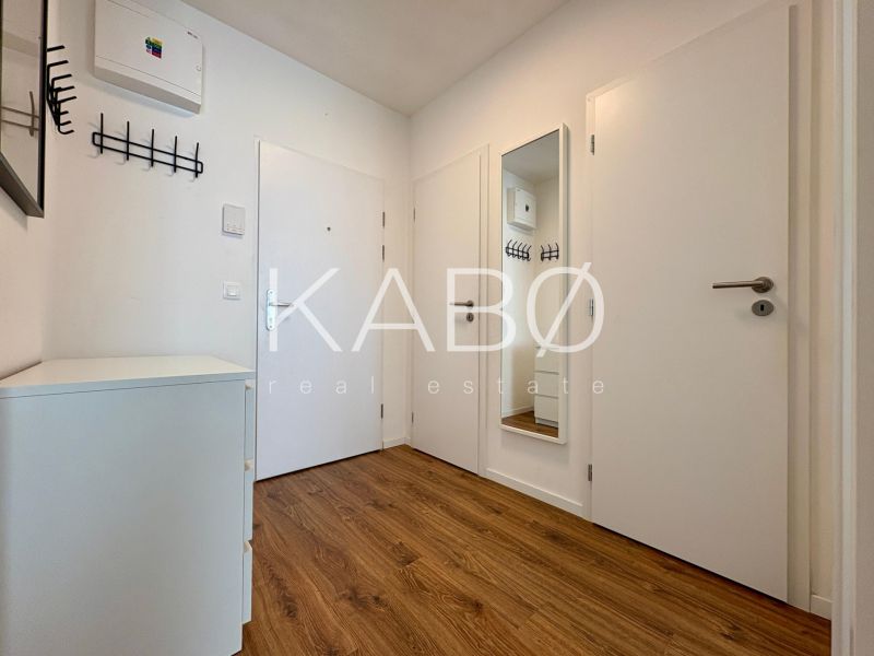 An entrance hall with a wooden decor floor and a mirror in a 2-room apartment.