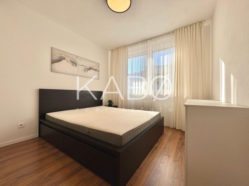 A bright bedroom with a bed, artwork on the wall, and a wooden decor floor in a 2-room apartment.