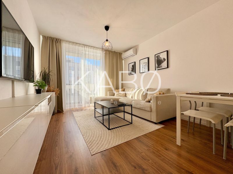 Living room with a sofa and TV, floor with wood decor in a 2-room apartment.