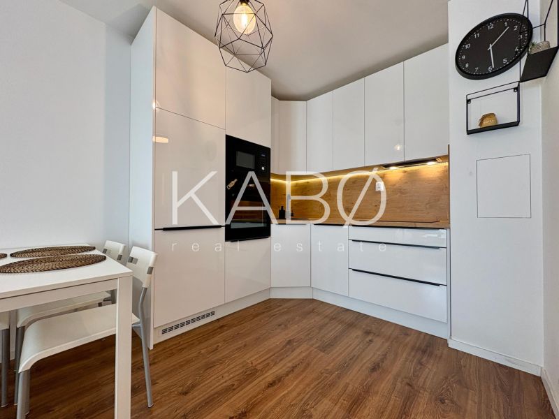 A kitchen in a 2-room apartment with white cabinets and a wood-patterned floor.