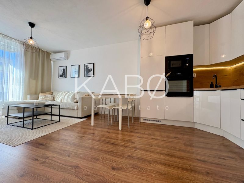 A bright living space in a 2-room apartment with a kitchenette and a wooden decor floor.