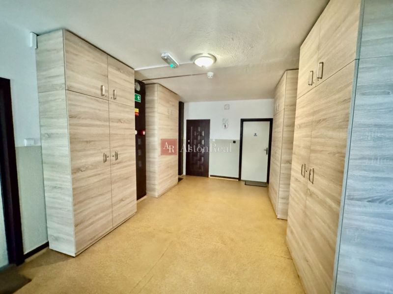 A hallway with a wooden decor floor and wardrobes in a 2-room apartment.