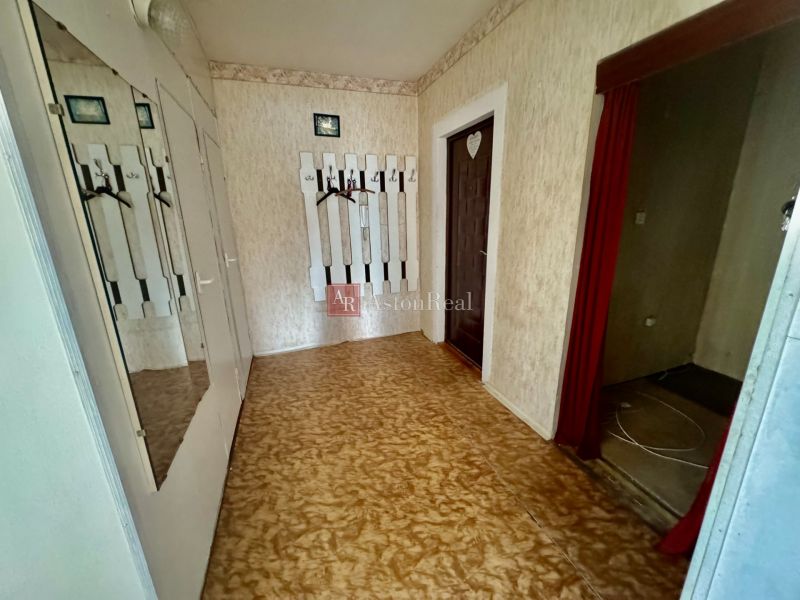 Interior of a 2-room apartment with a wall hanger, mirror, and floor with wooden decor.