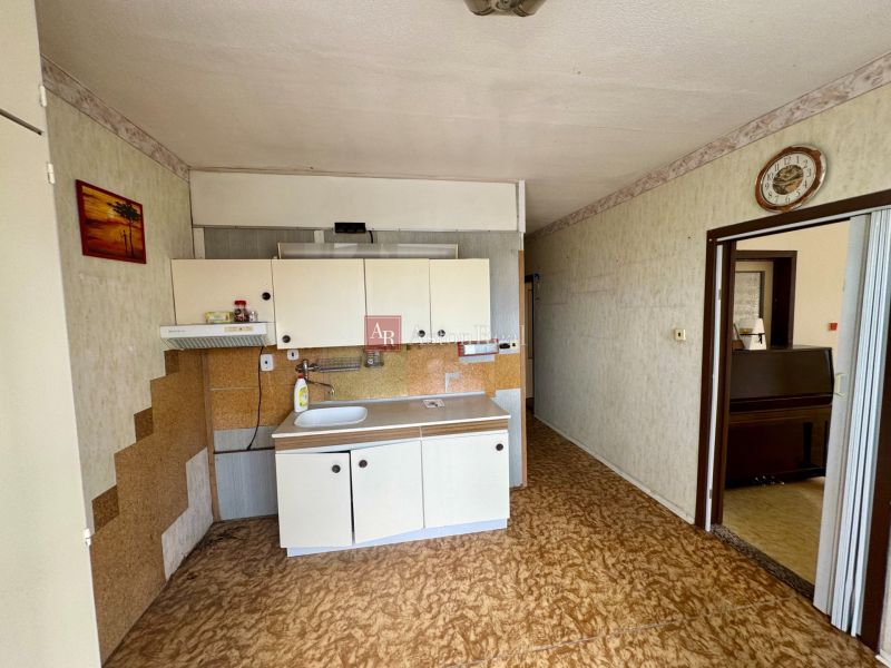 A kitchen in a 2-room apartment with a wooden decor floor and white cabinets.