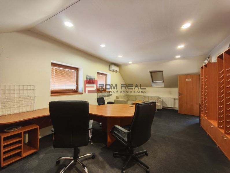An office in a production area with a round table and black chairs.