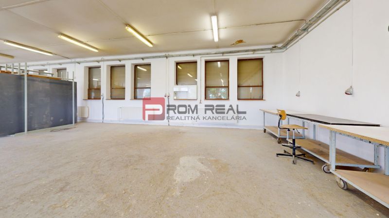 Production facilities with concrete flooring, tables, and lighting for workshop activities.