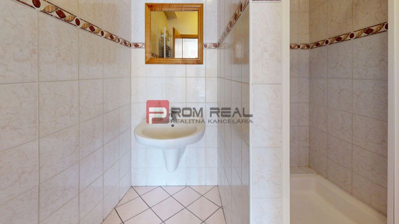 A bathroom in a production facility with a white sink and a mirror on the tiles.