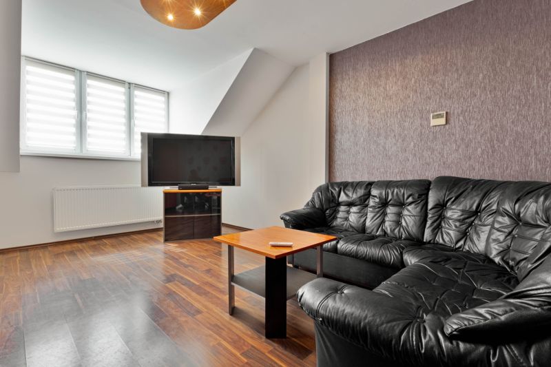 Living room with a black sofa set, television, and wooden decor flooring in a two-room apartment.