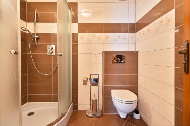 Bathroom with ceramic tiles, shower, and wall-hung toilet in a 2-room apartment.