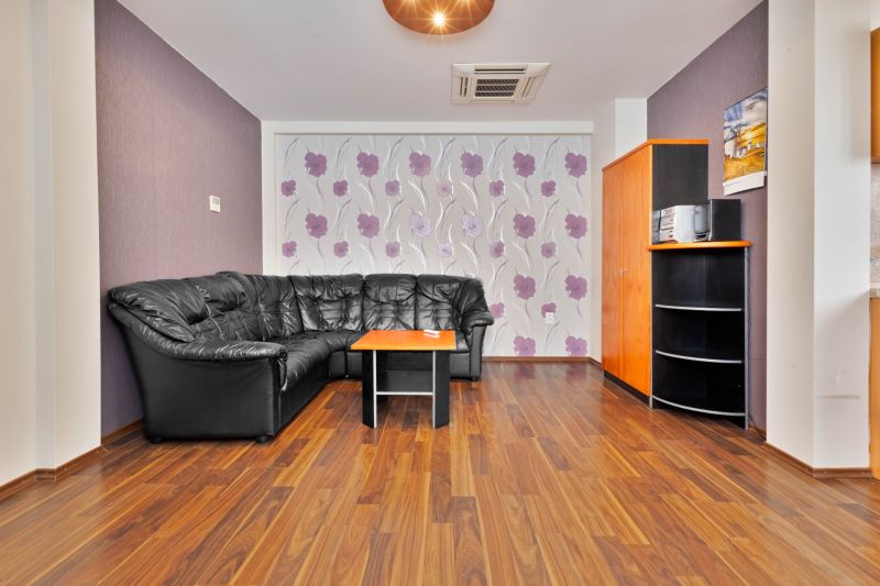 Living room with a sofa and a wooden decor floor in a 2-room apartment.