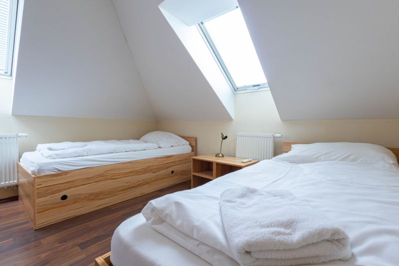Attic room in a 2-room apartment with beds; floor with wooden decor.
