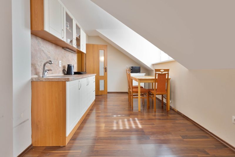 A kitchen with a slope, a dining table, and a wooden decor floor in a 2-room apartment.