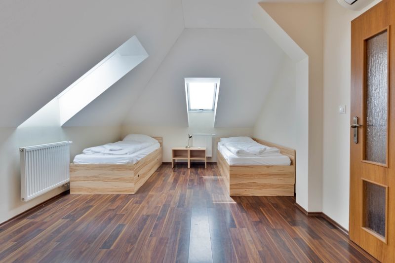 Two beds, a slanted roof, and a floor with a wooden decor in a 2-room apartment.