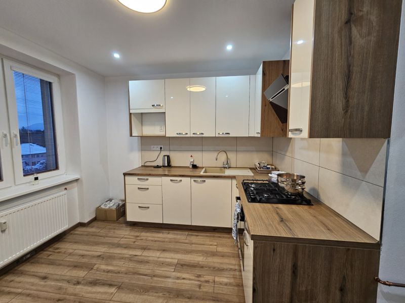 A kitchen in a 2-room apartment with white cabinets and a wooden decor floor.