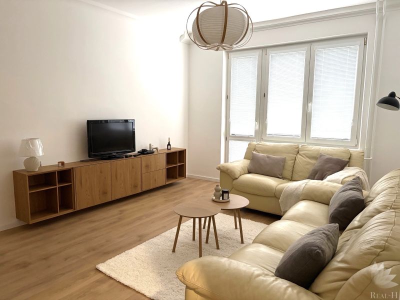 Living room in a three-room apartment with a beige sofa and a wooden decor floor.