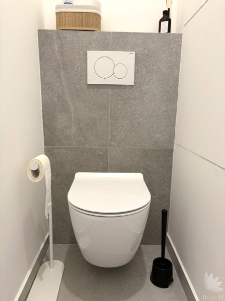 A minimalist bathroom with a tiled floor and a wall-mounted toilet in a 3-room apartment.