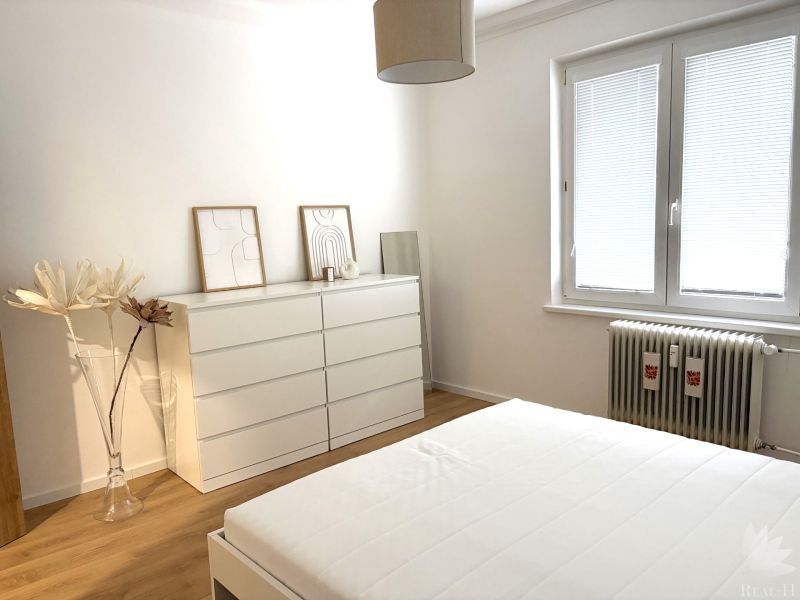 Bedroom with a dresser, bed, and wooden decor flooring in a 3-room apartment.