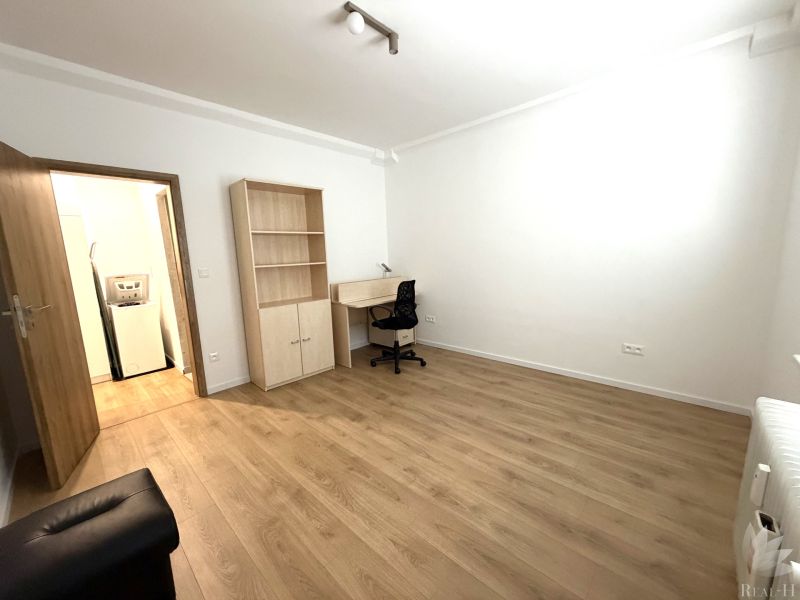 A room in a 3-room apartment with a desk and a wooden decor floor.