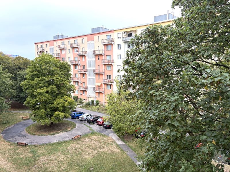 The exterior of an apartment building on Sklenárova Street in Bratislava-Nivy surrounded by greenery and cars.