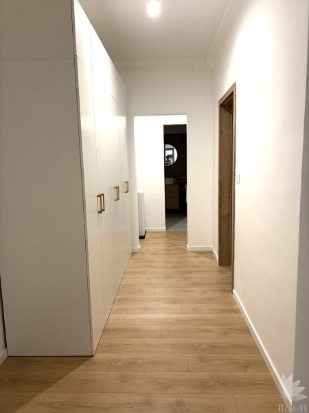 A hallway with a white wardrobe and a wooden decor floor in a 3-room apartment.