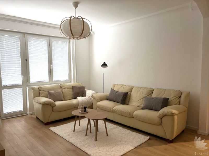 A bright living room with cream sofas, a carpet, and a wooden decor floor.