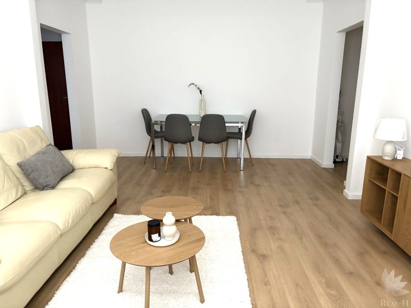 Living room in a 3-room apartment with a cream sofa and a wooden decor floor.