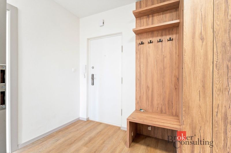 A kitchen unit in a 2-room apartment with a wooden decor floor and a dark countertop.