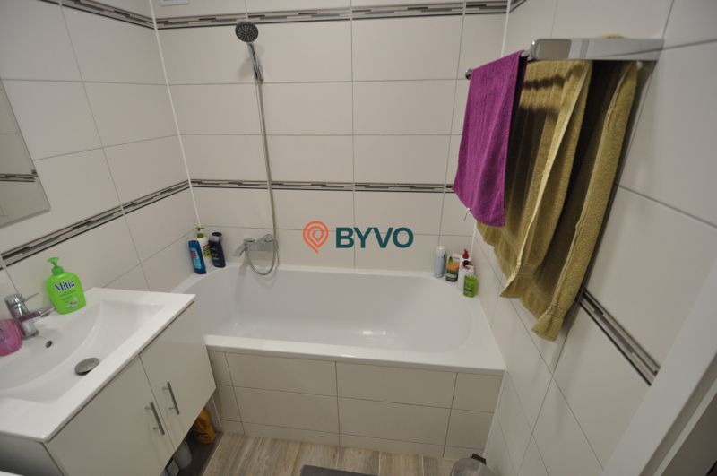 Bathroom with a white bathtub and sink in a 2-room apartment.