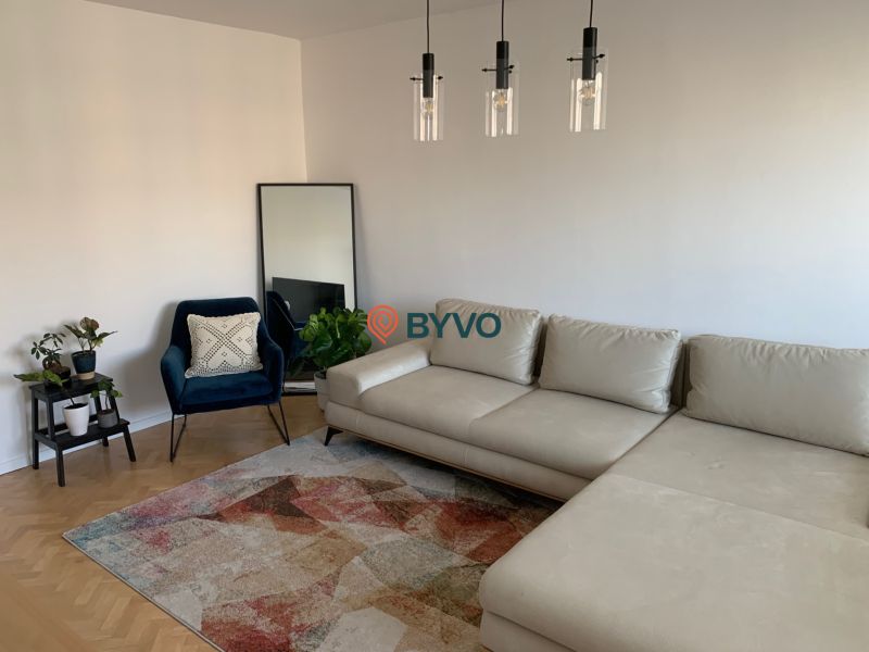 Living room in a two-room apartment with a sofa, an armchair, and a wooden decor floor.