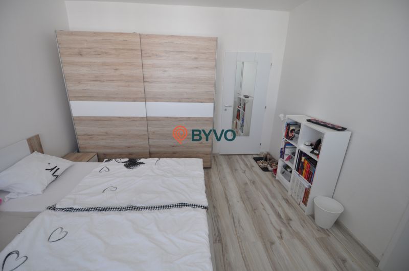 Bedroom in a 2-room apartment with wood-patterned flooring and a wardrobe.