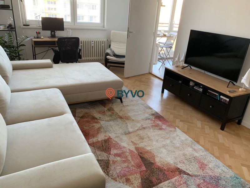 Living room with a sofa, desk, television, and wooden decor flooring.