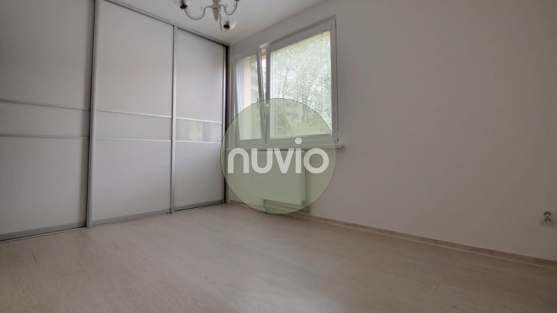 A room in a 3-room apartment, white wardrobe, wood-patterned floor, large window.