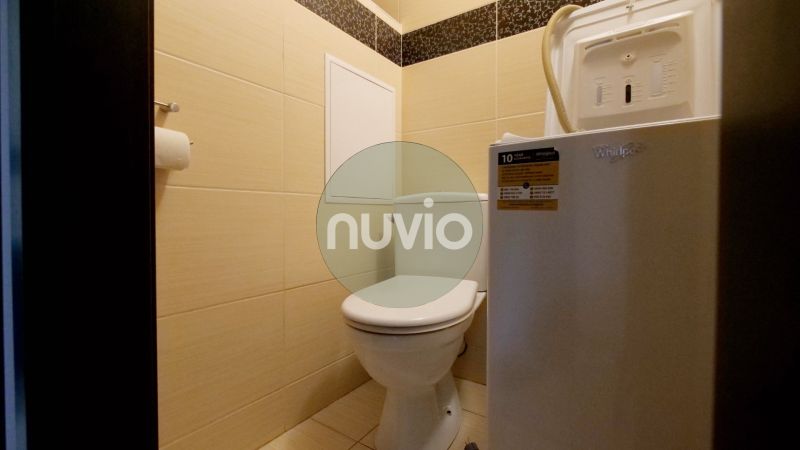 Bathroom with toilet and washing machine in a 3-room apartment, light wall tiles.