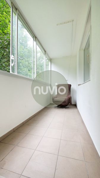 Enclosed balcony with a chair and tiles in a 3-room apartment.