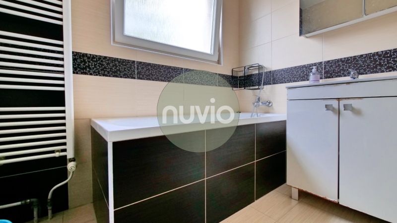 A bathroom with a shower, sink, and warm radiator in a 3-room apartment.