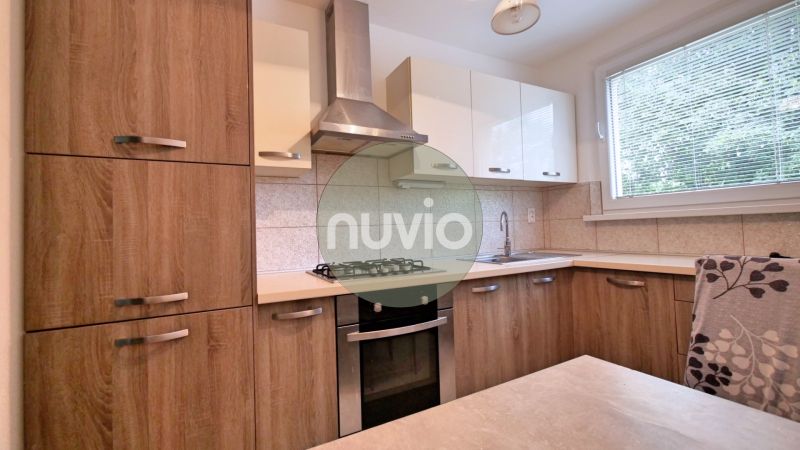 A kitchen in a 3-room apartment with wooden cabinets and a stove.