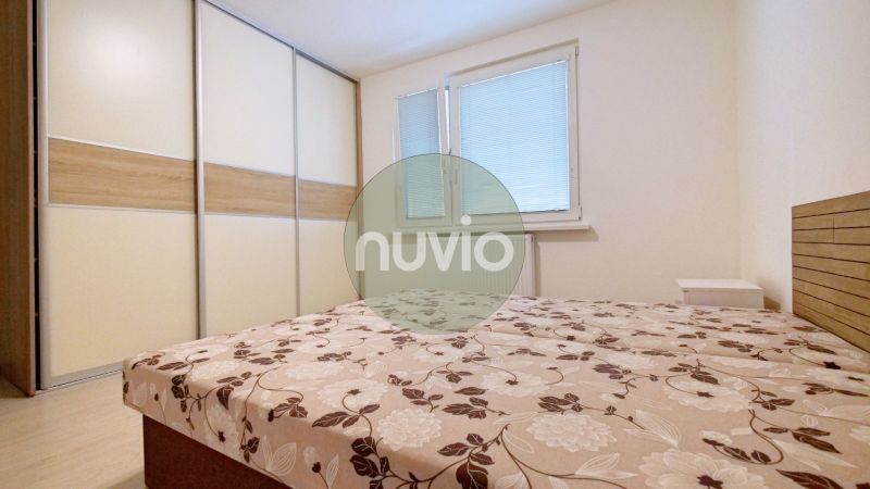 A bedroom in a 3-room apartment with a large wardrobe and a bed with floral bedding.