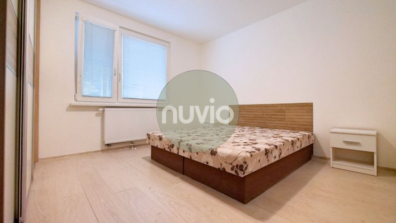 A bedroom in a 3-room apartment with a bed, a nightstand, and a floor with a wooden decor.