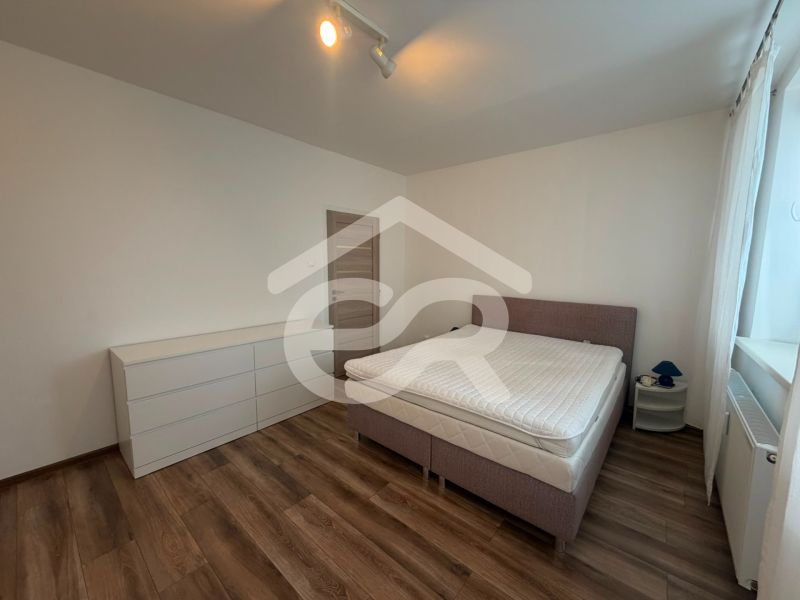 Bedroom in a 2-room apartment with a bed, dresser, and floor with a wood decor.