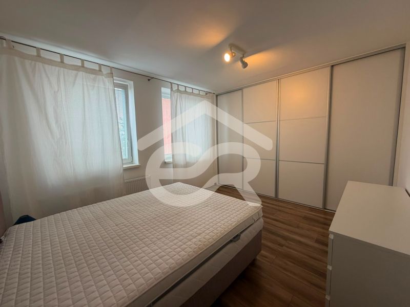 A bedroom with built-in wardrobes and a bed, complemented by a wooden decor floor in a two-room apartment.