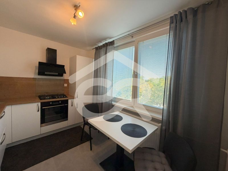 A kitchen in a 2-room apartment with a white kitchen unit and a view from the window.