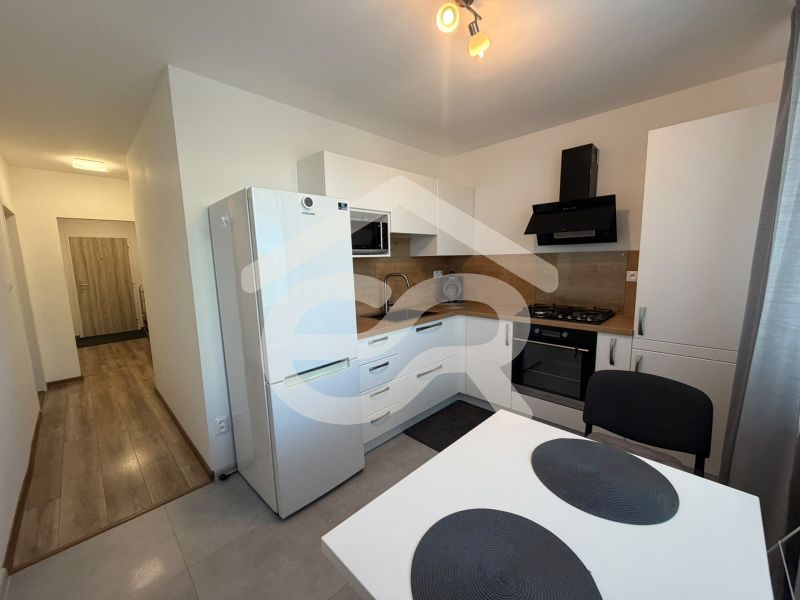 A kitchen in a 2-room apartment with a white kitchen unit and a floor with a wood decor.