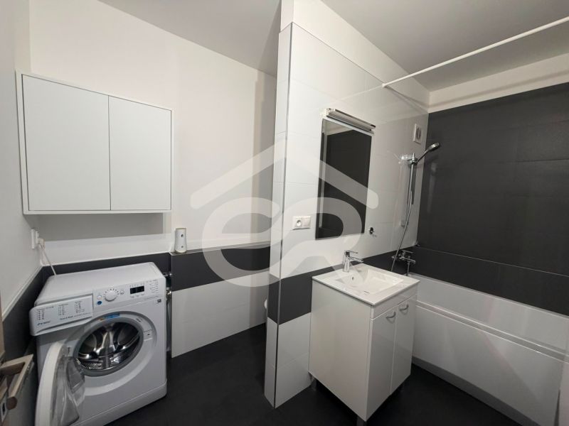 Bathroom in a 2-room apartment with a bathtub, sink, and washing machine.