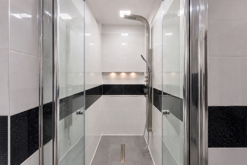A shower corner in a 3-room apartment with a large showerhead and black tiles.